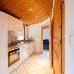 Kitchen with wooden ceiling, white cabinets, view into living room.