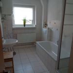 Badezimmer mit Badewanne, Dusche, Waschbecken und Fenster.