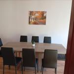 Esszimmer mit Holztisch, sechs Stühlen und Wandbild.