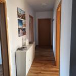 Flur mit Holzboden, weißen Wänden und Bildern an der Wand.