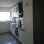 Küche mit weißen Schränken, Arbeitsplatte und Fenster.