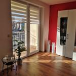 Wohnzimmer mit Blick auf Balkon, rote Wand und weißer Sideboard.