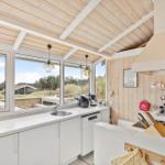Kitchen with white cabinets, wooden ceiling, and large windows to the garden.