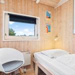 Bedroom with bed, chair, and window overlooking the landscape.