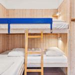 Room with bunk bed, wooden walls, and bedside lamps.