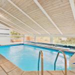Indoor pool with wooden ceiling and windows to the outside.