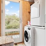 Laundry room with washing machine and dryer. Entrance to terrace with dune view.