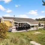A yellow house with terrace, grill, and swing in the garden.