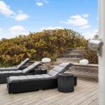 Deck with loungers and tables, view of hedges and steps.