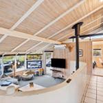Living area with wooden ceiling, TV, and view of terrace.