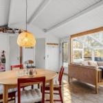 Essbereich mit runden Tisch und roten Stühlen. Wohnbereich mit Sofa und Glasfront.