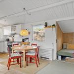 Küche, Essbereich und Schlafbereich in einem Ferienhaus mit Holzwänden und weißen Decken.