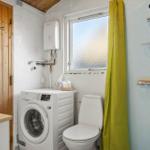 Badezimmer mit Dusche, Toilette und Waschmaschine. Holztür und Fenster mit Steinverkleidung.
