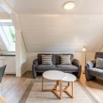 Wohn- und Küchenbereich mit Sofa, Sessel und Esstisch.