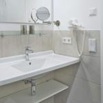 Badezimmer mit Waschbecken, Spiegel und Handtuchhalter.