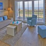 Wohnzimmer mit Sofa, Sessel und Balkonblick aufs Meer