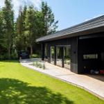 Moderne Villa mit Holzterrasse, Grünfläche und Grillbereich im Freien.