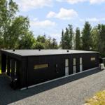 Schwarzes Haus mit modernem Design, umgeben von Bäumen und Gras.