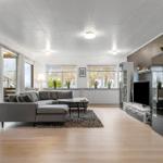 Wohnzimmer mit Sofa, Fernseher und Blick auf Terrasse
