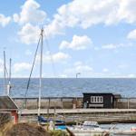 Hafen mit Booten und Blick auf das Meer unter blauem Himmel mit weißen Wolken.