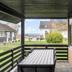 Terrasse mit Tisch und Stühlen, Blick auf Grünfläche und Haus.