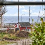 Rotes Haus am Wasser mit Masten und Blick auf See