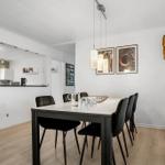 Esszimmer mit Tisch, Stühlen und Küchenbereich im Hintergrund.