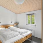 Ein Schlafzimmer mit Holzbett, Fenster und Decke.