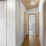 Flur mit Kleiderschrank, Holzdecke und Blick in die Küche.