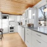 Kitchen with white cabinets, wooden ceiling, and window to the outside.