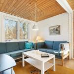 Living room with blue sofa, white table, and wooden ceiling. View of forest through windows.