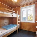 Room with bunk bed, wooden walls, and window with view outside.