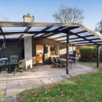 Terrace with table and chairs under roof, view into living area.