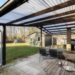 Terrace with seating and shelter. In background, a shed and playground.