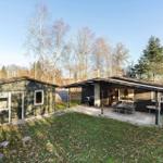 House with terrace, garden, and trees in the background.