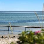 A view of the sea with a boat and a wooden pier in the foreground.