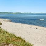 Beach with a white boat in the water and green vegetation along the shore.