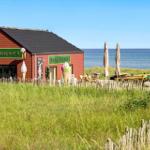 Red building with ice cream stands by the beach. Outdoor terrace with tables and umbrellas.