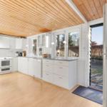 Kitchen with white cabinets, wooden floor, and roof. Door leads outside.