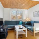 Living room with sofa, coffee table, and TV. Wooden ceiling and window with view of forest.