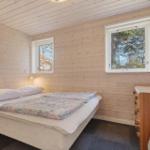 Bedroom with bed, two windows, and wood paneling.