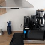 Küche mit Herd, Mikrowelle und Kaffeemaschine.