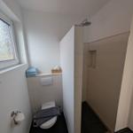 Badezimmer mit Dusche, Toilette und Fenster