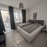Schlafzimmer mit Doppelbett, Fenster und Sitzgelegenheit.