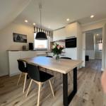 Essbereich mit Tisch, Stühlen und Küchenzeile unter schrägem Dach.