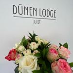 Blumenstrauß vor Wand mit Schriftzug DÜNEN LODGE JUIST