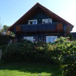 Haus mit Balkon, Garten und Blumen. Sonniger Tag.