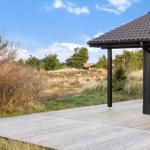 Wooden terrace with view of grassland and trees under blue sky.