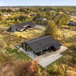 Two modern houses on dunes with terraces and view of the landscape.