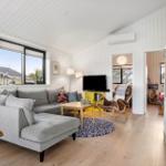 Living room with gray sofa, wooden floor, and TV.